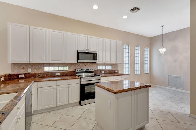 kitchen with light tile patterned flooring, stainless steel appliances, pendant lighting, and white cabinets