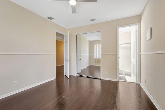 unfurnished bedroom featuring ceiling fan, dark hardwood / wood-style flooring, a closet, and ensuite bath