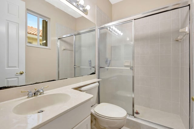 bathroom featuring toilet, vanity, and a shower with door