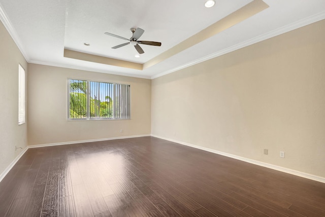 empty room featuring ceiling fan, dark hardwood / wood-style flooring, crown molding, and a tray ceiling