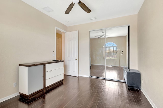 unfurnished bedroom with ceiling fan, a closet, and dark hardwood / wood-style flooring