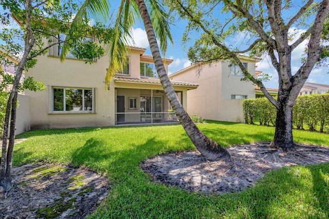 back of property featuring a sunroom and a lawn