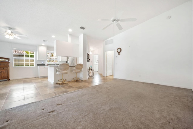 unfurnished living room with lofted ceiling, light colored carpet, and ceiling fan