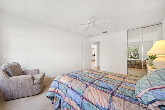 bedroom with light colored carpet, ceiling fan, and a closet