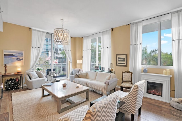 living room with wood-type flooring, a healthy amount of sunlight, and an inviting chandelier