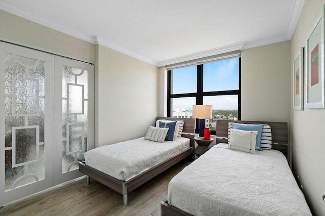 bedroom with french doors, crown molding, a wall of windows, and wood-type flooring