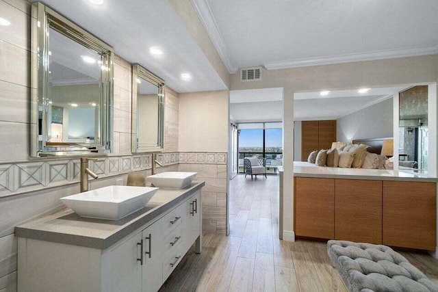 bathroom with hardwood / wood-style flooring, tile walls, vanity, and ornamental molding