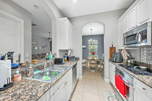 kitchen featuring light tile patterned floors, white cabinetry, stainless steel appliances, ceiling fan with notable chandelier, and sink