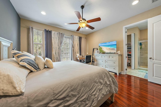 bedroom featuring ceiling fan, a walk in closet, wood-type flooring, and ensuite bath