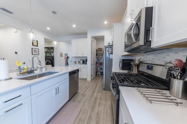 kitchen with sink, white cabinetry, stainless steel appliances, and hanging light fixtures