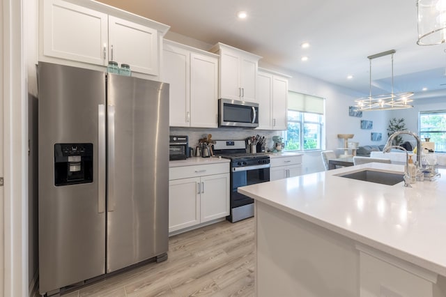 kitchen featuring decorative light fixtures, sink, white cabinetry, and stainless steel appliances