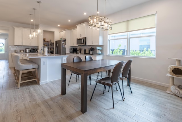 dining room featuring sink, light hardwood / wood-style flooring, and a notable chandelier