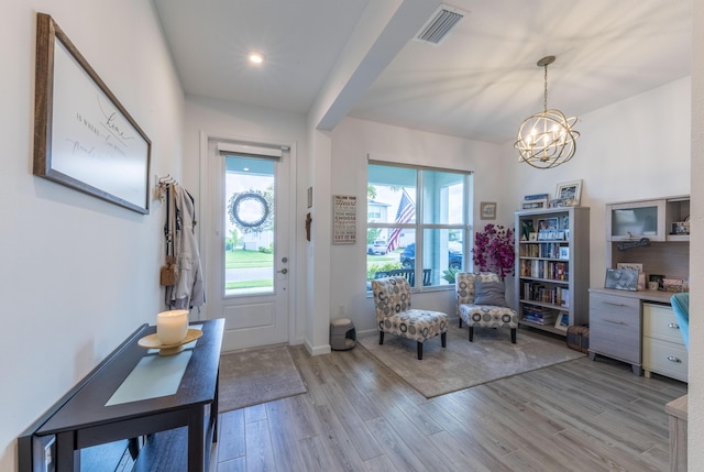 foyer featuring plenty of natural light, an inviting chandelier, and light hardwood / wood-style flooring