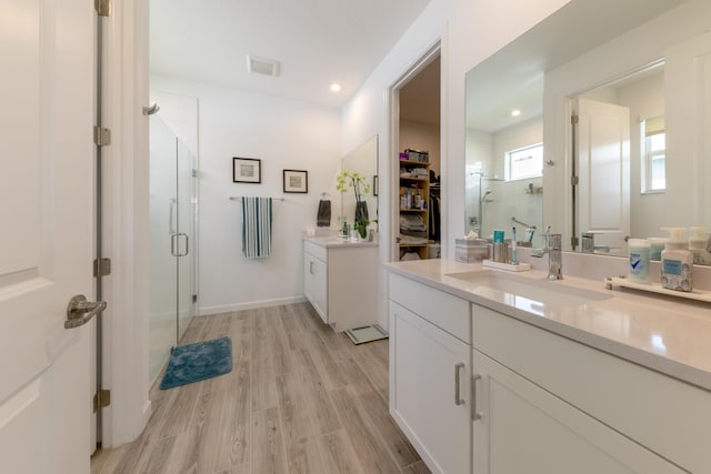 bathroom featuring a shower with shower door and vanity