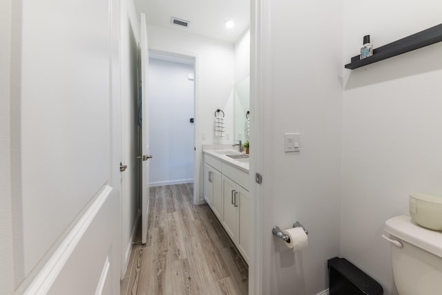 bathroom with toilet, vanity, and hardwood / wood-style flooring