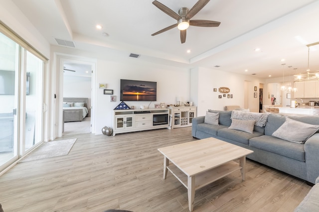 living room featuring ceiling fan, light hardwood / wood-style flooring, and a raised ceiling