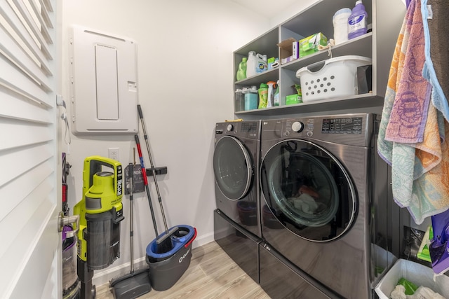 laundry area featuring washer and clothes dryer, light wood-type flooring, and electric panel