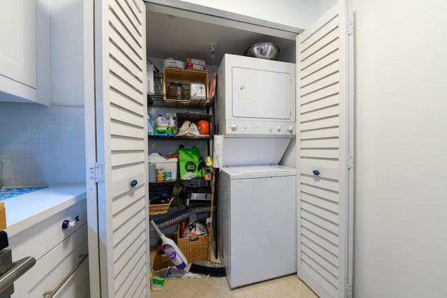 clothes washing area with light tile patterned floors and stacked washer / dryer