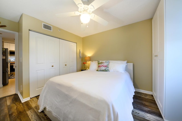 bedroom with dark wood-type flooring, a closet, fridge, and ceiling fan