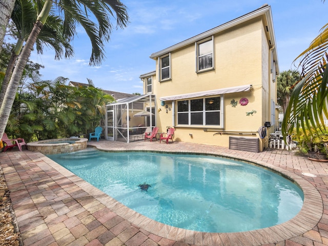 view of swimming pool featuring glass enclosure, a patio area, and an in ground hot tub