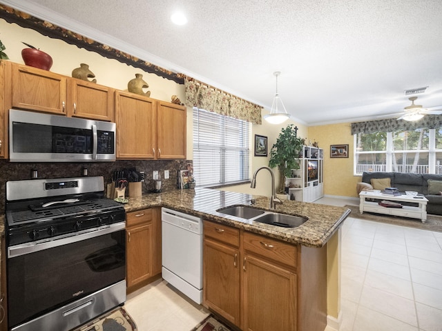 kitchen featuring sink, a textured ceiling, ornamental molding, and stainless steel appliances