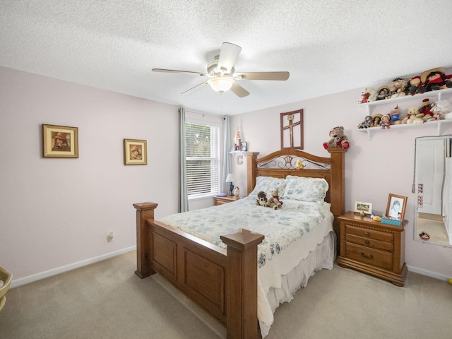 bedroom with ceiling fan, light colored carpet, and a textured ceiling