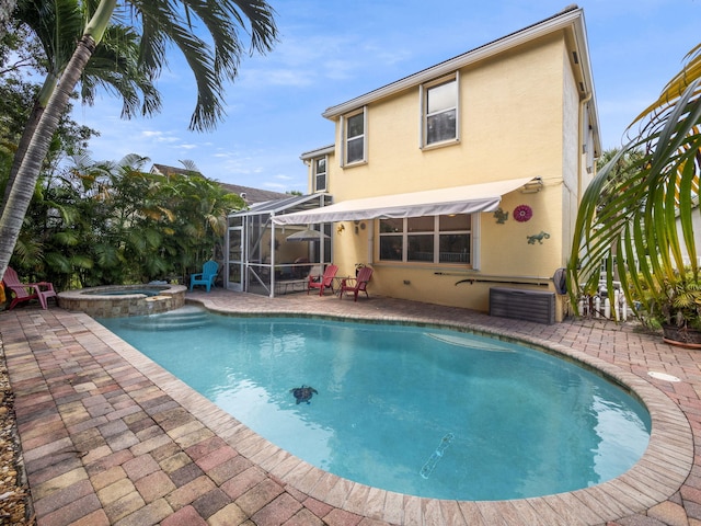 view of swimming pool with glass enclosure, an in ground hot tub, and a patio