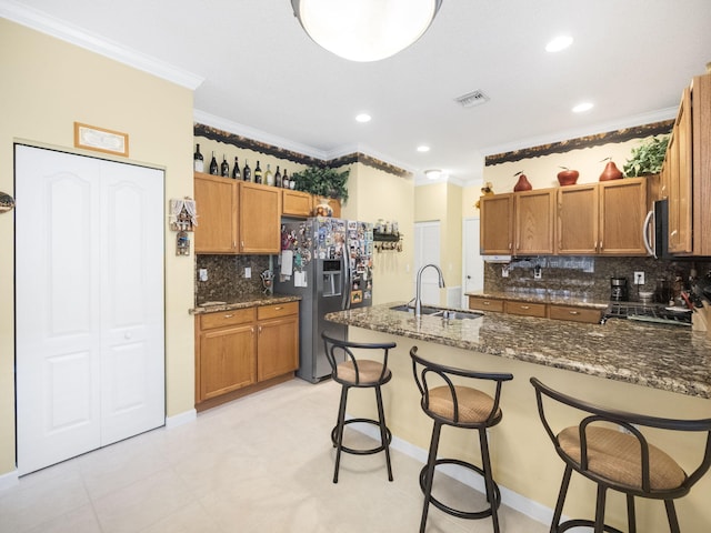 kitchen featuring dark stone countertops, kitchen peninsula, sink, crown molding, and appliances with stainless steel finishes