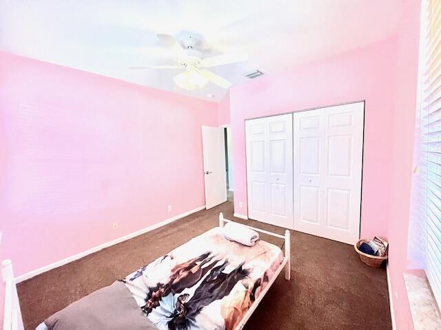 carpeted bedroom featuring ceiling fan and a closet