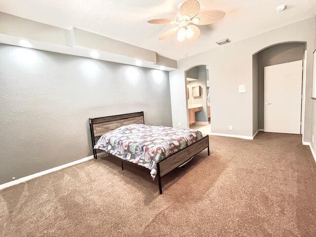 carpeted bedroom featuring a textured ceiling, ceiling fan, and ensuite bath