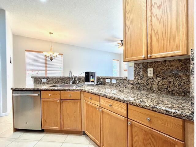 kitchen featuring backsplash, dishwasher, stone countertops, ceiling fan with notable chandelier, and sink