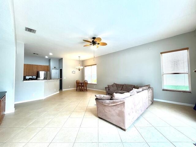 tiled living room featuring ceiling fan with notable chandelier