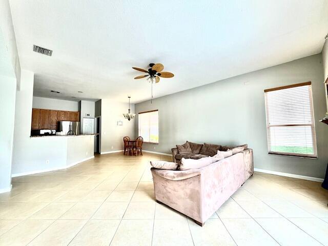 living room featuring a healthy amount of sunlight, light tile patterned floors, and ceiling fan with notable chandelier