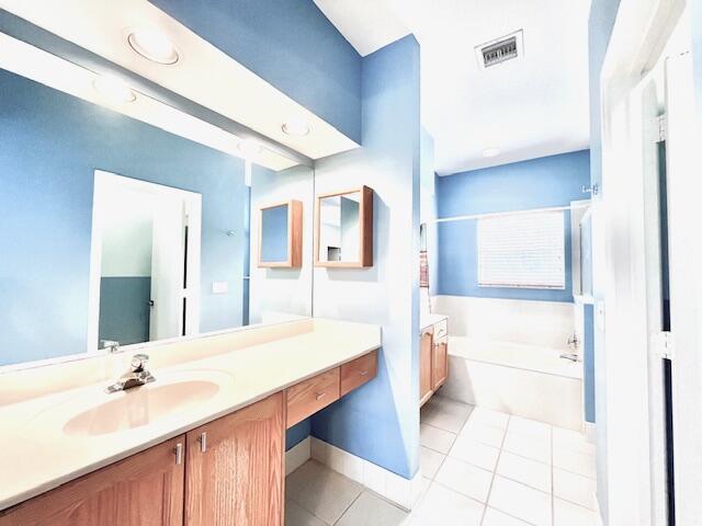 bathroom with tile patterned floors, a washtub, and vanity