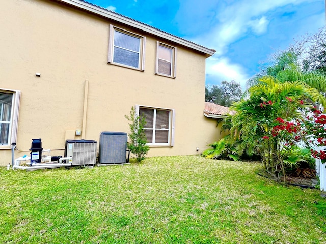 back of property with a lawn and central AC