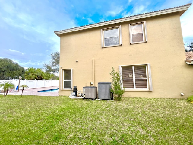 back of house featuring a fenced in pool, cooling unit, and a yard