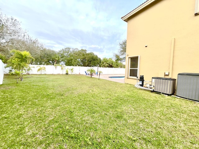 view of yard with a fenced in pool and central AC unit