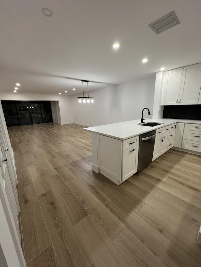 kitchen featuring white cabinetry, kitchen peninsula, pendant lighting, stainless steel dishwasher, and sink