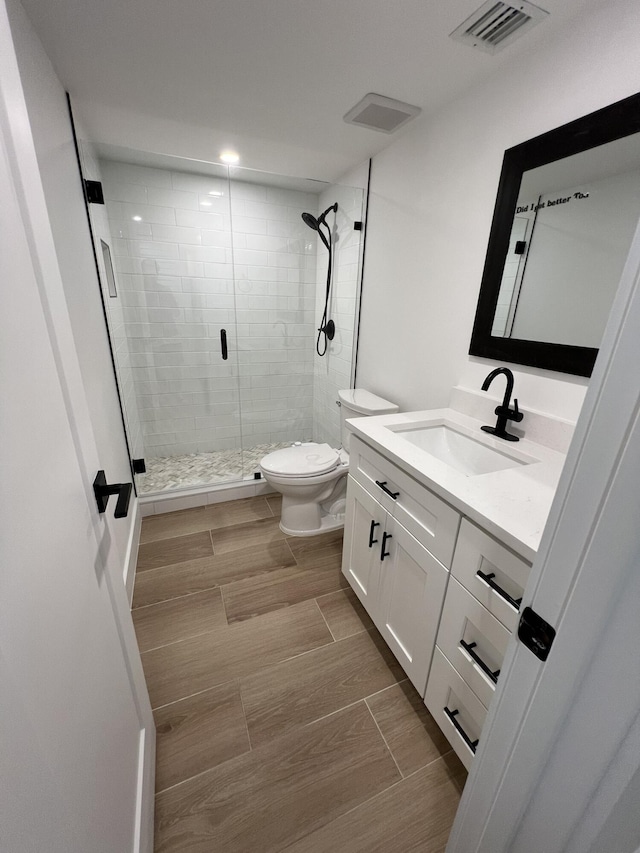 bathroom with toilet, an enclosed shower, and vanity