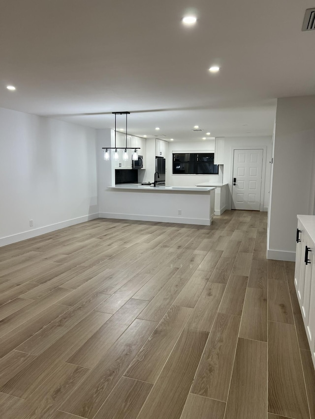 unfurnished living room with sink and light hardwood / wood-style flooring