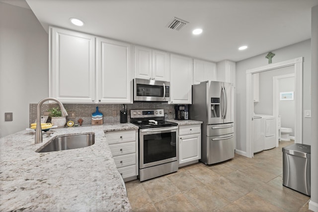 kitchen featuring separate washer and dryer, sink, white cabinets, light stone counters, and stainless steel appliances