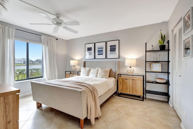 tiled bedroom with ceiling fan, a closet, and a water view