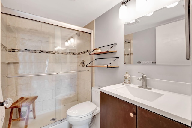 bathroom featuring a shower with shower door, toilet, and vanity