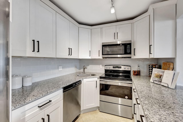 kitchen with appliances with stainless steel finishes, track lighting, white cabinetry, and light stone countertops