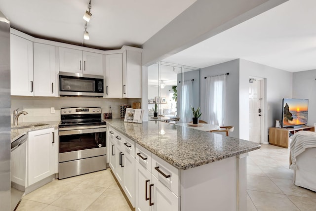 kitchen featuring light tile patterned flooring, sink, white cabinetry, light stone countertops, and stainless steel appliances