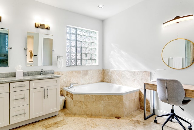 bathroom with tiled tub and vanity