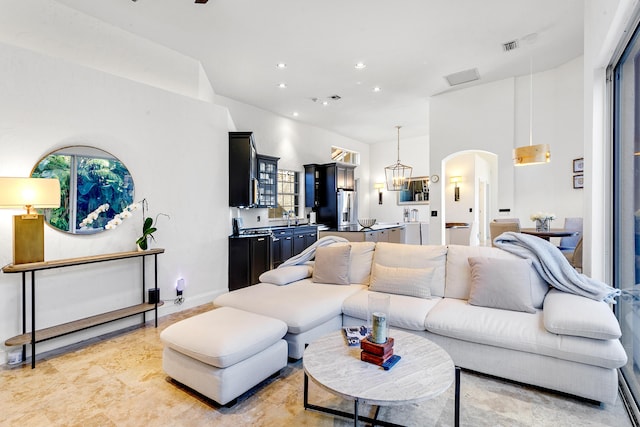 living room with sink, a towering ceiling, and an inviting chandelier