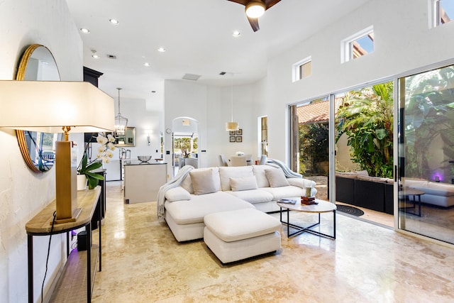 living room with ceiling fan and a towering ceiling