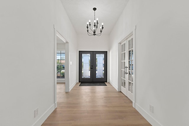 entrance foyer featuring a chandelier, light hardwood / wood-style flooring, and french doors