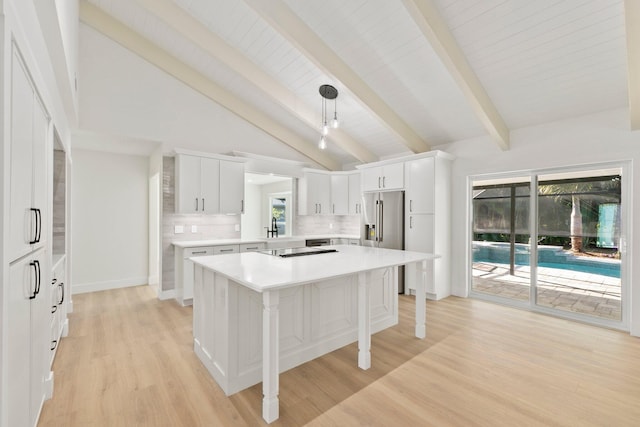 kitchen featuring white cabinets, a kitchen island, decorative light fixtures, backsplash, and light wood-type flooring